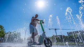 Tomas aus Berlin fährt mit seinem E-Scooter durch den Wasserbrunnen vor dem Bundeskanzleramt in Berlin, Deutschland, am Mittwoch, dem 2. Juli 2025.