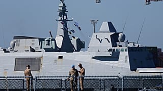 Une frégate française entre dans le port, suivie par des marins à bord du navire allemand de la FINUL, le FGS Nordrhein-Westfalen, à Limassol, à Chypre, le mardi 10 mars 2026.