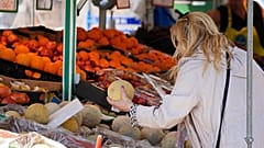 Eine Frau prüft in Essen den Preis einer Wassermelone; in Deutschland steigen die Lebensmittelpreise stark, Mai 2023.