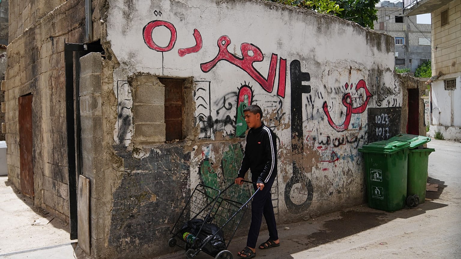 شاب فلسطيني يمر بجوار لوحة جدارية مكتوب عليها "حق العودة" في مخيم الدهيشة للاجئين بالضفة الغربية الجمعة 15 مايو 2026.