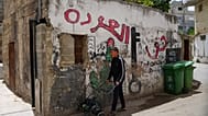 شاب فلسطيني يمر بجوار لوحة جدارية مكتوب عليها "حق العودة" في مخيم الدهيشة للاجئين بالضفة الغربية الجمعة 15 مايو 2026.