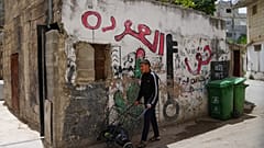 شاب فلسطيني يمر بجوار لوحة جدارية مكتوب عليها "حق العودة" في مخيم الدهيشة للاجئين بالضفة الغربية الجمعة 15 مايو 2026.