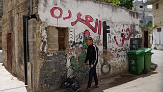 شاب فلسطيني يمر بجوار لوحة جدارية مكتوب عليها "حق العودة" في مخيم الدهيشة للاجئين بالضفة الغربية الجمعة 15 مايو 2026.