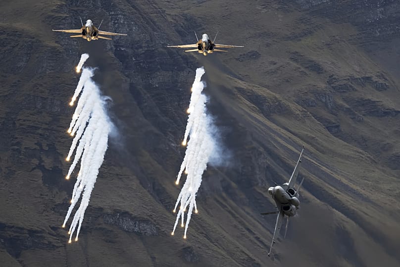 McDonnell Douglas F/A-18C Hornet fighter jets of the Swiss Air Force drop flares during the annual airshow of the Swiss Army in the Axalp area near Meiringen, 18 October, 2023