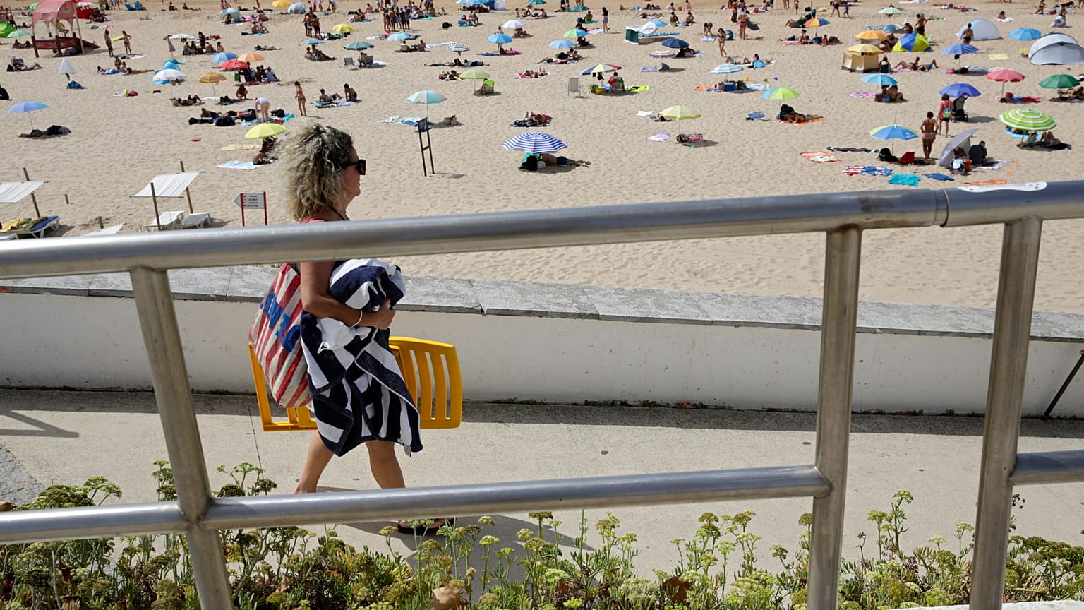 Pessoas passeiam à beira-mar na praia de Carcavelos, em Carcavelos, nos arredores de Lisboa, no sábado, 14 de agosto de 2021
