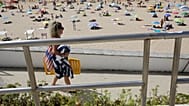 Pessoas passeiam à beira-mar na praia de Carcavelos, em Carcavelos, nos arredores de Lisboa, no sábado, 14 de agosto de 2021