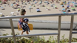 Menschen spazieren am Strand von Carcavelos am Stadtrand von Lissabon, Samstag, dem 14. August 2021.