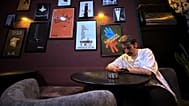 A man looks at his smart phone as he sits under posters of Hollywood movies at a cafe in Tehran, 8 May 2026