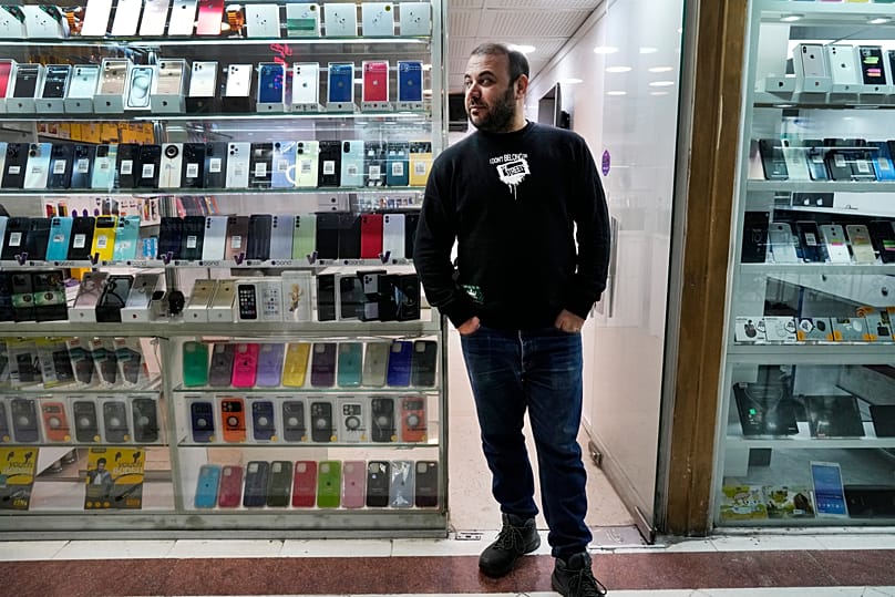 FILE: A worker at a mobile phone store waits for customers in downtown Tehran, 21 February 2024
