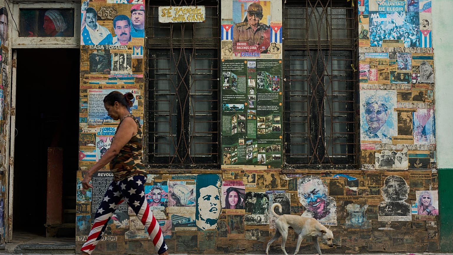 A woman wearing U.S. flag motif pants walks past a building that houses an art installation on the Cuban Revolution