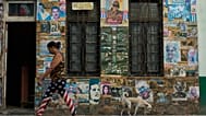 A woman wearing U.S. flag motif pants walks past a building that houses an art installation on the Cuban Revolution