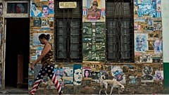 A woman wearing U.S. flag motif pants walks past a building that houses an art installation on the Cuban Revolution