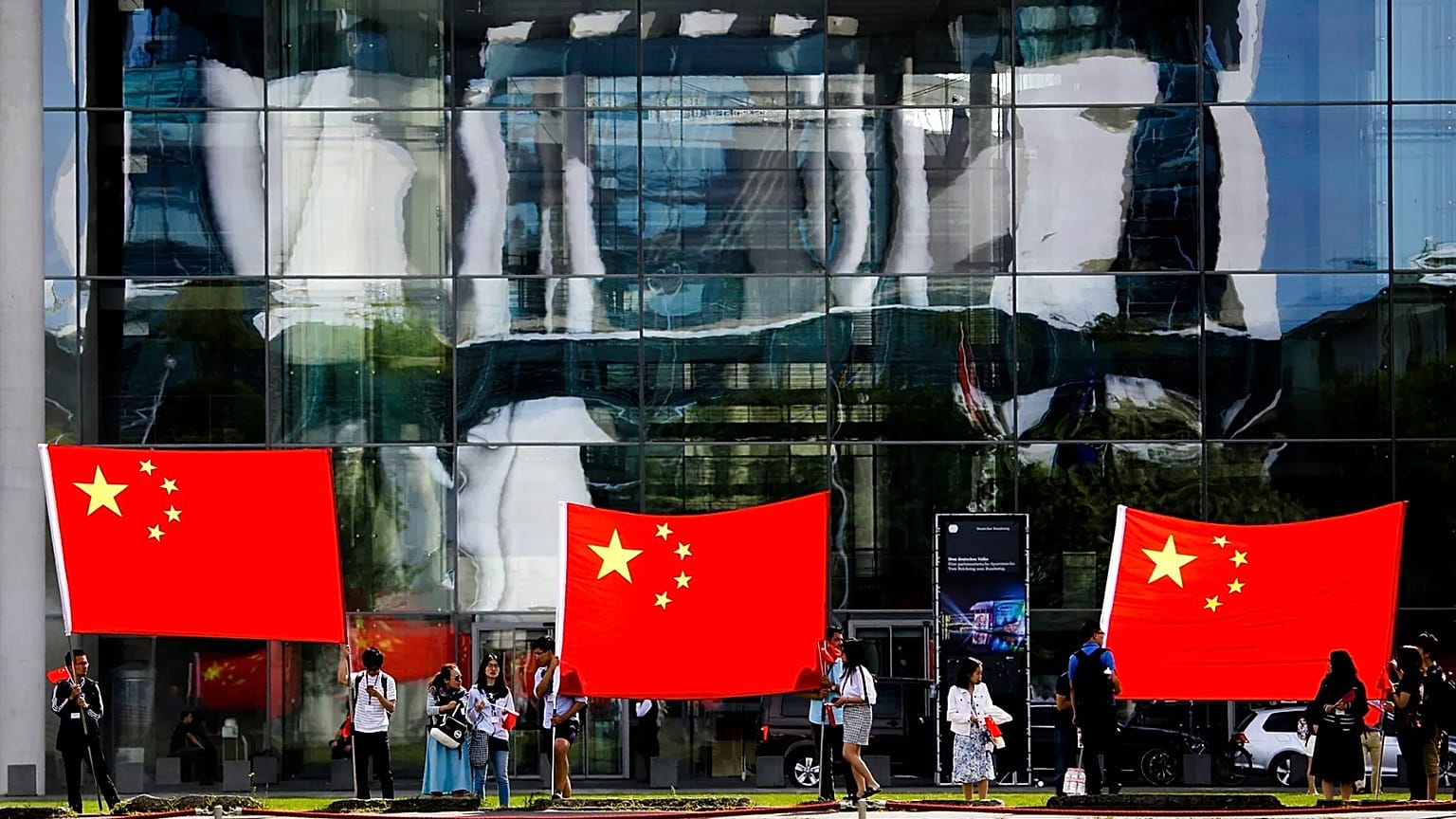 People show Chinese flags in front of the chancellery building in Berlin, 9 July, 2018