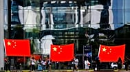 People show Chinese flags in front of the chancellery building in Berlin, 9 July, 2018