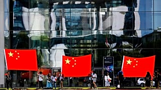 People show Chinese flags in front of the chancellery building in Berlin, 9 July, 2018