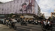 Motorbikes drive past a billboard showing the late Iranian Supreme Leader Ayatollah Ali Khamenei, who was killed in the U.S. and Israel strikes on Feb. 28, in downtown Tehran,