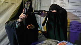 عنصر من قوات "الباسيج" التابعة للحرس الثوري الإيراني تقدّم إرشادات حول كيفية التعامل مع بندقية هجومية خلال حصة تدريب على السلاح في طهران، إيران، الثلاثاء 19 مايو/أيار 2026. 