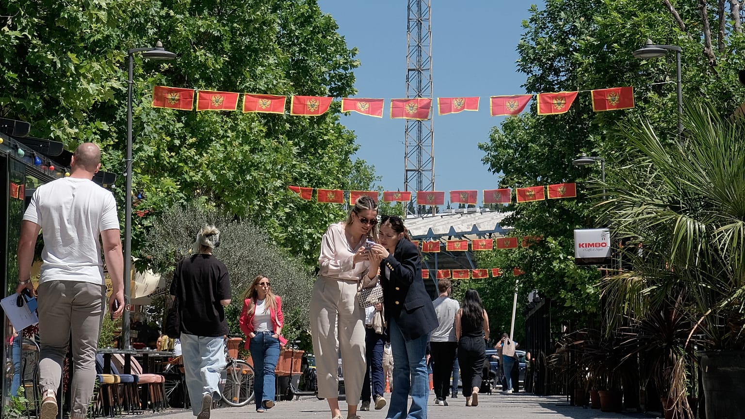 Karadağ’ın başkenti Podgorica’da ulusal bayraklarla süslenmiş bir sokak. / Yayalar, 18 Mayıs 2026 Pazartesi