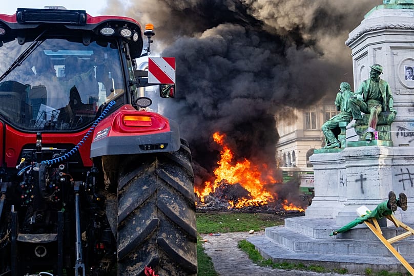 Des manifestants brûlent des déchets près d’une statue et d’un tracteur lors d’une mobilisation d’agriculteurs européens près du Parlement européen à Bruxelles, jeudi 18 décembre 2025.