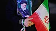 متظاهر يحمل ملصقًا للمرشد الأعلى الإيراني المقتول آية الله علي خامنئي، الذي قُتل في الغارة الأمريكية والإسرائيلية في 28 فبراير، وعلمًا إيرانيًا خلال تجمع مؤيد للحكومة