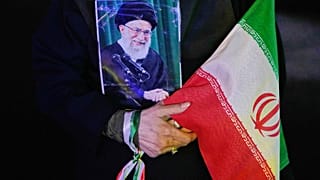 متظاهر يحمل ملصقًا للمرشد الأعلى الإيراني المقتول آية الله علي خامنئي، الذي قُتل في الغارة الأمريكية والإسرائيلية في 28 فبراير، وعلمًا إيرانيًا خلال تجمع مؤيد للحكومة