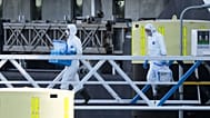 Persone in tuta protettiva trasportano oggetti non identificati mentre sbarcano dalla nave da crociera MV Hondius al porto di Rotterdam, Paesi Bassi, lunedì 18 maggio 2026.