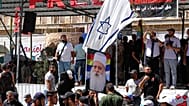 رجل يلوح بالعلم الإسرائيلي فوق صورة الشيخ موفق طريف، الزعيم الروحي للدروز في إسرائيل، خلال تجمع أسبوعي في السويداء، جنوب سوريا، في 20 سبتمبر 2025.
