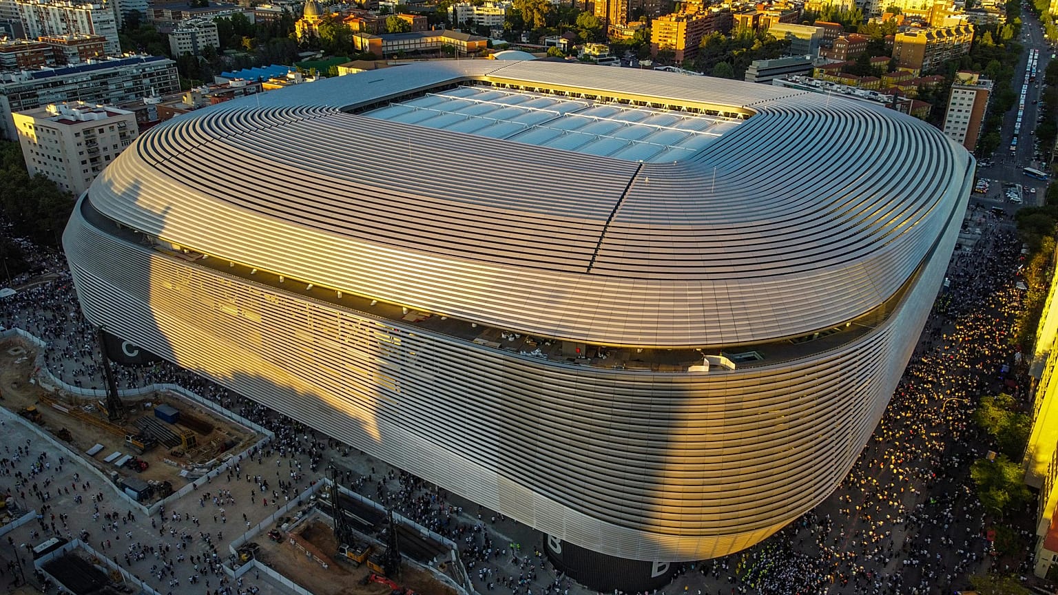 Toma aérea del Estadio Santiago Bernabéu en Madrid durante el atardecer mostrando su arquitectura moderna