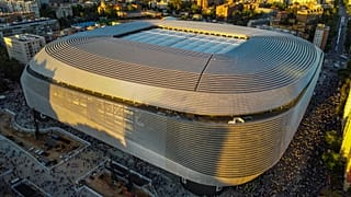 Toma aérea del Estadio Santiago Bernabéu en Madrid durante el atardecer mostrando su arquitectura moderna