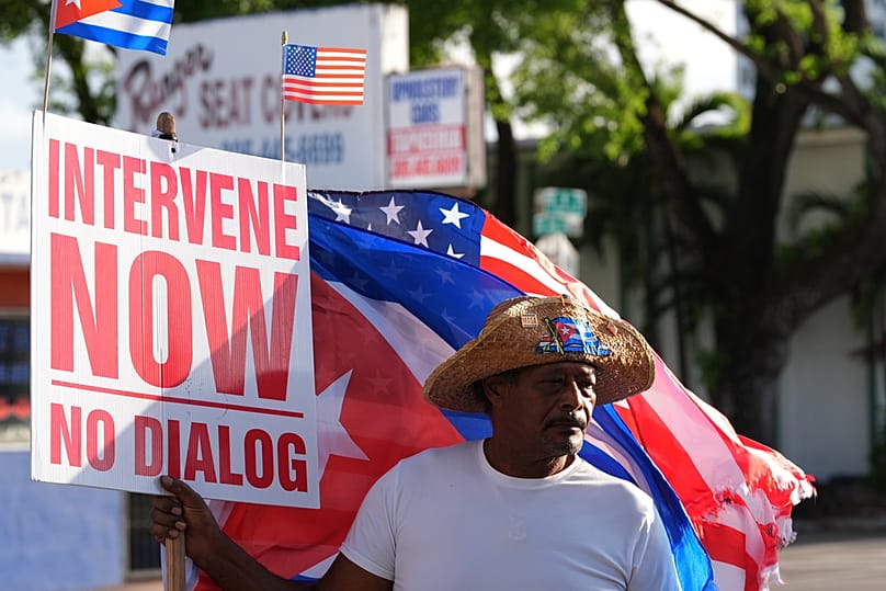A protester holds a sign calling for American intervention in Cuba, after federal prosecutors announced charges against Raul Castro, in Miami, Wednesday, May 20, 2026
