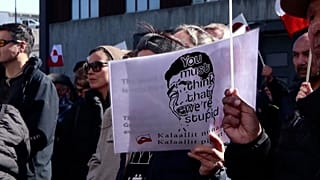 Demonstrant hält ein Schild mit der Aufschrift: „Ihr haltet uns wohl für dumm.“