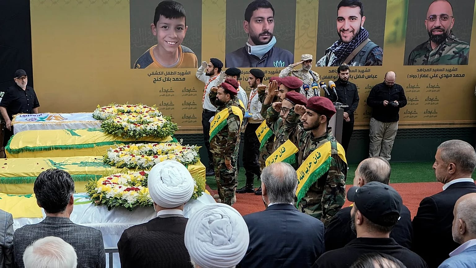 يؤدي مقاتلو حزب الله التحية العسكرية وهم يقفون بجوار نعوش أربعة ضحايا قُتلوا يوم الثلاثاء إثر انفجار أجهزة النداء المحمولة الخاصة بهم، وذلك خلال موكب جنازتهم في الضاحية الجنوب