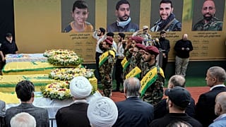 يؤدي مقاتلو حزب الله التحية العسكرية وهم يقفون بجوار نعوش أربعة ضحايا قُتلوا يوم الثلاثاء إثر انفجار أجهزة النداء المحمولة الخاصة بهم، وذلك خلال موكب جنازتهم في الضاحية الجنوب