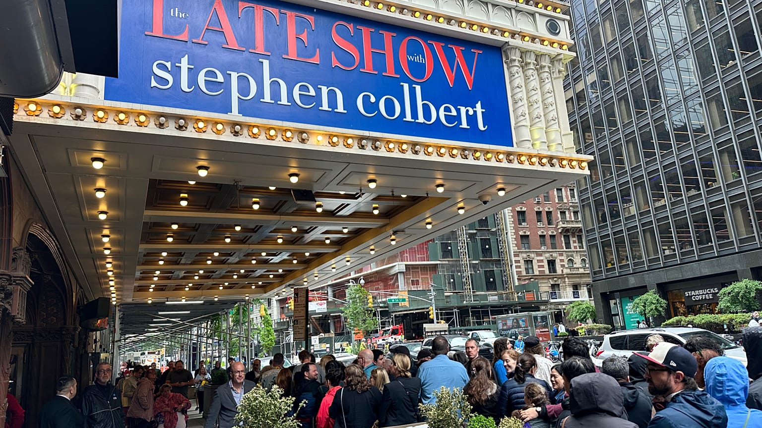 Fans line up in the rain outside the Ed Sullivan Theater in New York on Thursday, May 21, 2026, ahead of the final episode of "The Late Show with Stephen Colbert