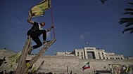 أحد مؤيدي حزب الله يلتقط صورة سيلفي وهو يلوح بعلم حزب الله بينما يقف على شجرة خارج السفارة الإيرانية في بيروت، لبنان
