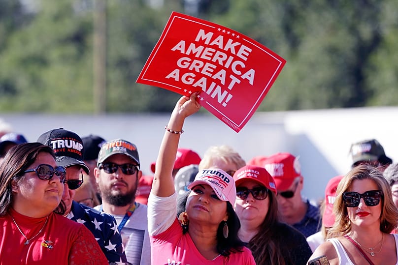 Um participante ergue um cartaz MAGA enquanto a multidão aguarda por Donald Trump, a 2 de novembro de 2023, em Houston. (AP Photo/Michael Wyke)