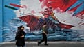People walk past a mural depicting a U.S. aircraft carrier under missile attack in downtown Tehran, Iran, Sunday, May 17, 2026.