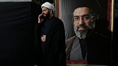 رجل دين يتحدث عبر هاتفه المحمول إلى جانب صورة للمرشد الأعلى الإيراني مجتبى خامنئي، طهران، إيران، الاثنين 18 مايو/أيار 2026. 
