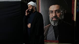 رجل دين يتحدث عبر هاتفه المحمول إلى جانب صورة للمرشد الأعلى الإيراني مجتبى خامنئي، طهران، إيران، الاثنين 18 مايو/أيار 2026. 