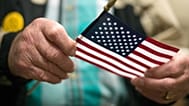 يحمل شيروين كالاندر، المحارب المخضرم في الحرب العالمية الثانية البالغ من العمر أربعة وتسعين عامًا، العلم الأمريكي بعد حفل التجنس.