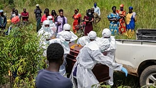 Trabalhadores da Cruz Vermelha preparam um caixão com o corpo de uma vítima de Ébola para sepultura no cemitério de Rwampara, em Bunia, Congo, sábado, 23 de maio de 2026.