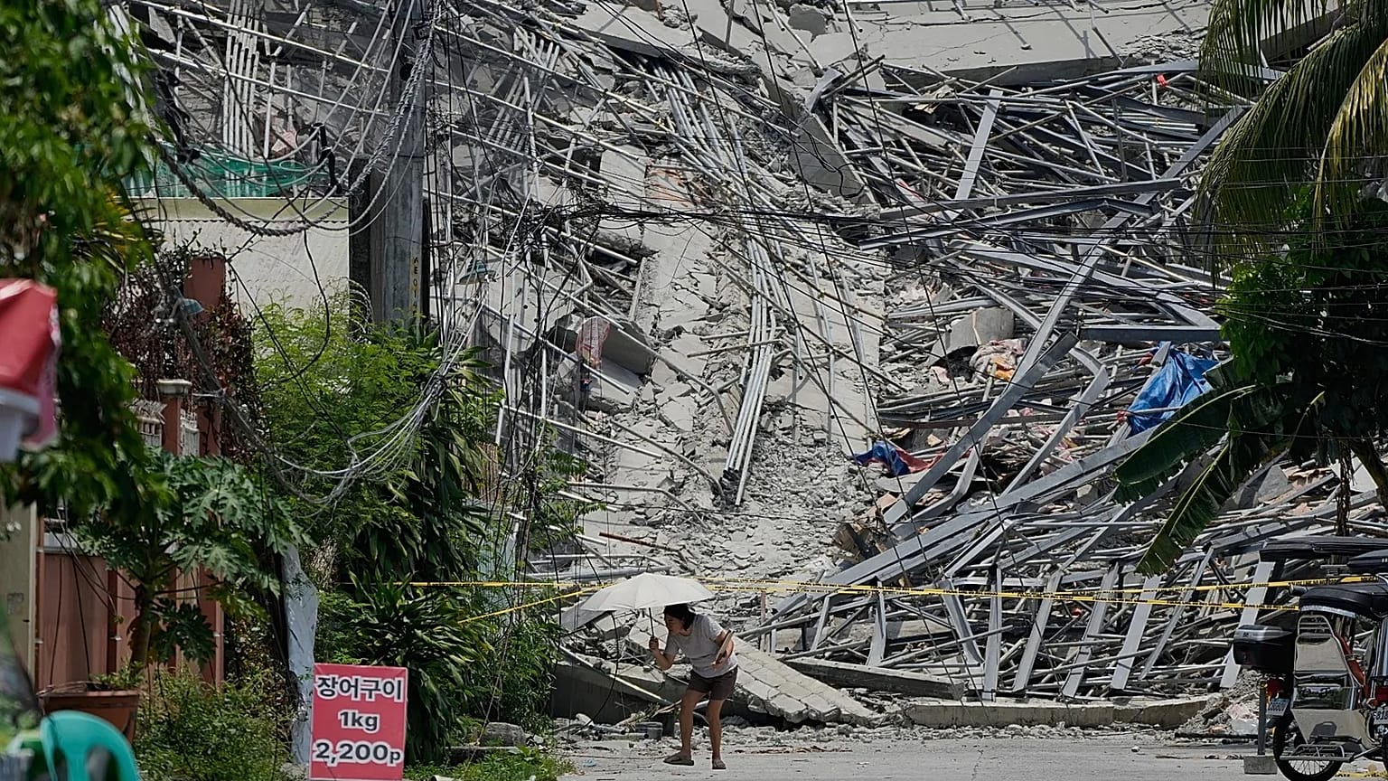 A woman walks past a collapsed building as search operations continue where multiple people are believed to be trapped in Angeles city, 25 May, 2026