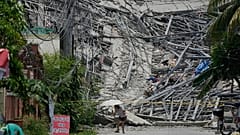 A woman walks past a collapsed building as search operations continue where multiple people are believed to be trapped in Angeles city, 25 May, 2026