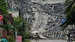 A woman walks past a collapsed building as search operations continue where multiple people are believed to be trapped in Angeles city, 25 May, 2026