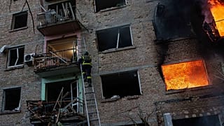 Un soccorritore sale su una scala per aiutare a evacuare i residenti da un edificio residenziale danneggiato dopo un attacco russo su Kyiv, in Ucraina, domenica 24 maggio 2026