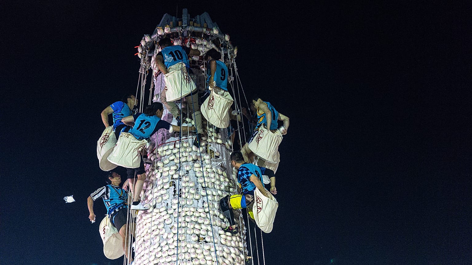 Des participants ramassent des brioches sur une tour couverte de brioches en plastique lors du festival des brioches sur l’île de Cheung Chau, à Hong Kong, le 25 mai 2026.