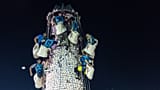 Uczestnicy zdejmują bułeczki z wieży pokrytej plastikowymi bułeczkami podczas Festiwalu Bułeczek na wyspie Cheung Chau w Hongkongu, w poniedziałek 25 maja 2026 r.