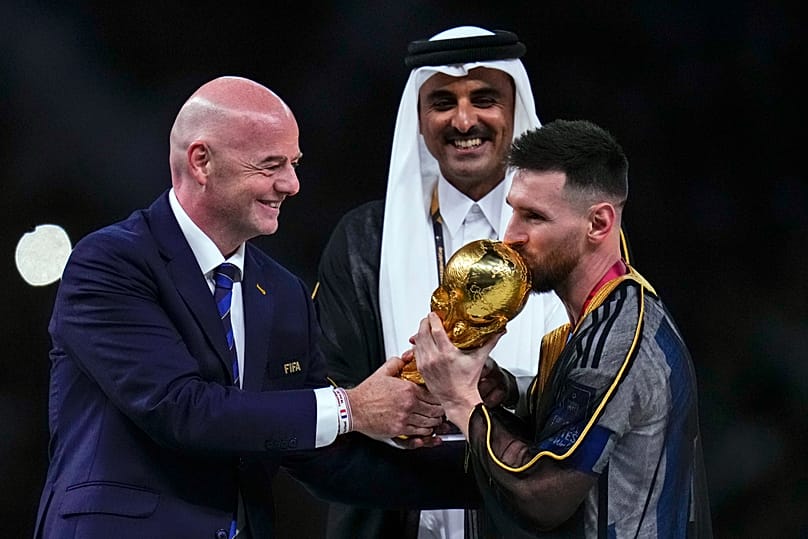 FILE - Argentina's Lionel Messi kisses the trophy presented by FIFA President Gianni Infantino, left, as The Emir of Qatar Sheikh Tamim bin Hamad Al Thani looks on.