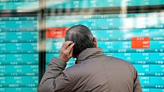 صورة تعبيرية_ شخص ينظر إلى لوحة إلكترونية تعرض أسعار الأسهم اليابانية في شركة أوراق مالية بطوكيو