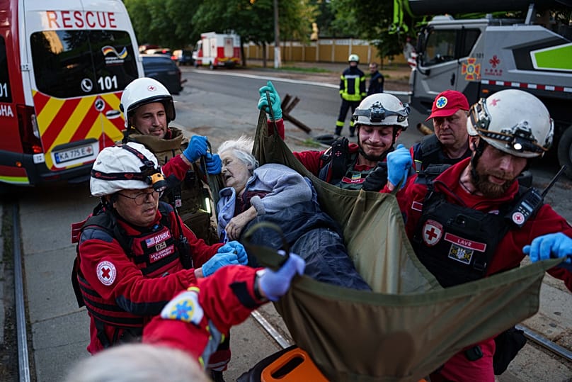 Red Cross volunteers carry an injured woman into an ambulance after a Russian strike on a residential neighborhood on Kyiv, Ukraine, on Sunday, May 24, 2026.